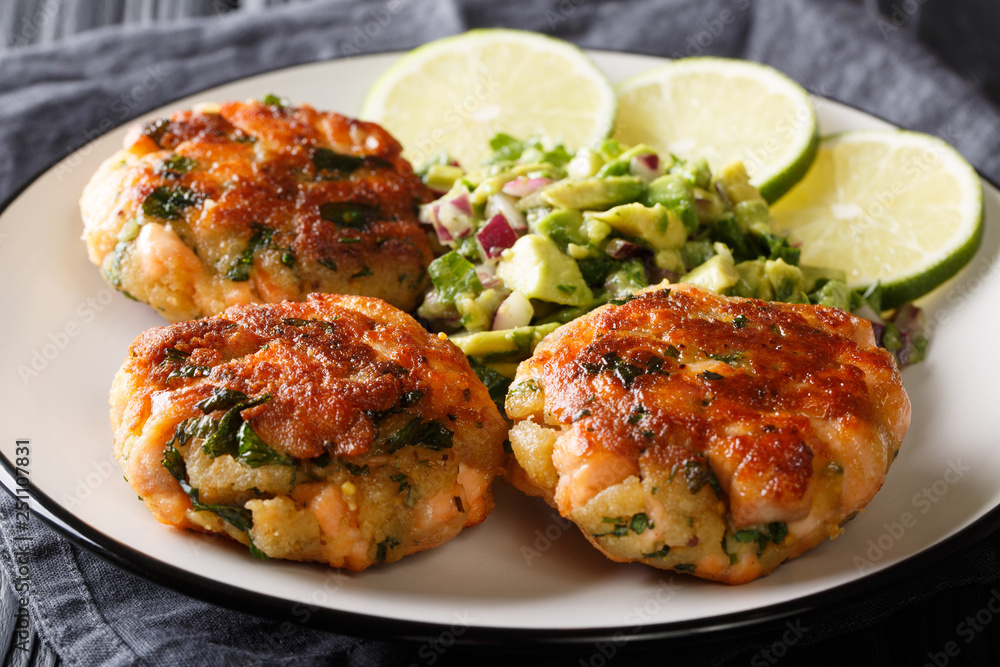 Healthy food salmon patties with fresh avocado salsa and lime closeup on a plate. horizontal Healthy food salmon patties with fresh avocado salsa and lime closeup on a plate. horizontal