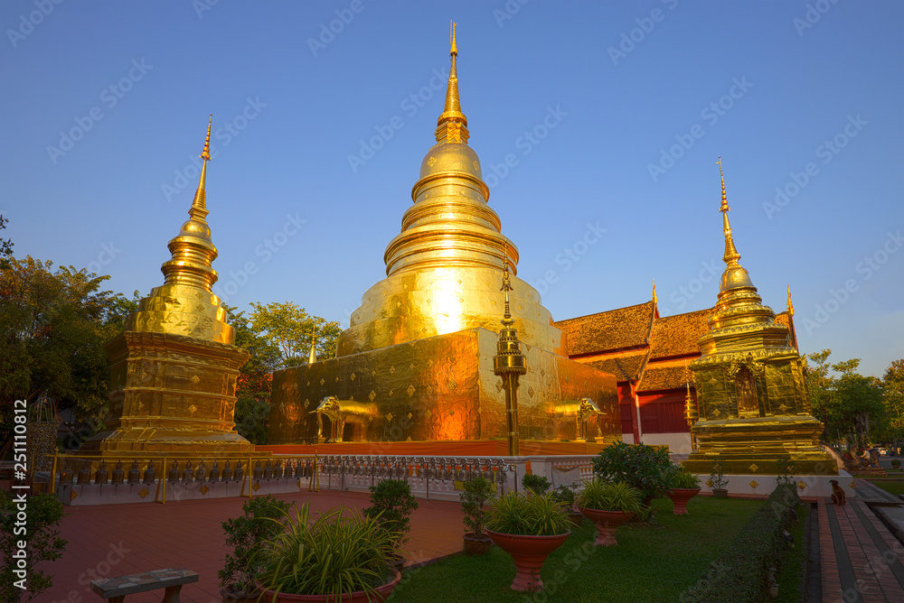 Fototapeta premium Złota chedi świątyni buddyjskiej Wat Phra Singh w słoneczny wieczór. Chiag Mai, Tajlandia