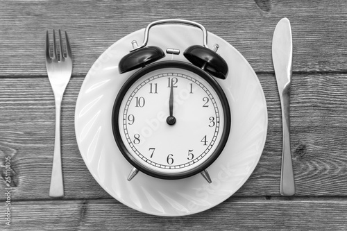 Alarm clock with fork and knife on the table. Time to eat, Breakfast, Lunch time and dinner concept. Black and White Concept