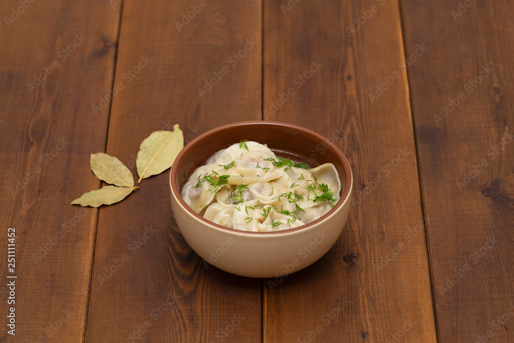 Russian pelmeni meat Dumplings with greens in the plate on wooden table. Tasty homemade meat dumplings.
