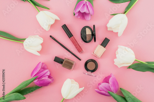 Beauty composition with tulips flowers and cosmetics on pink background. Top view. Flat lay.