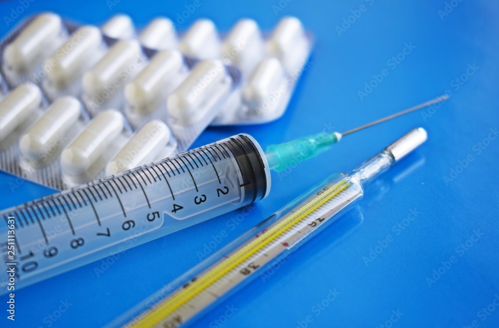 Medical preparation.A syringe and a thermometer on a blue background. Medical preparation.A syringe and a thermometer on a blue background.