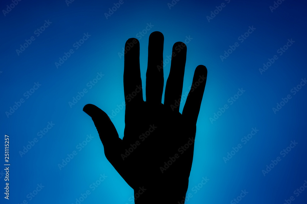 Clean silhouette of a hand against a blue background with a spotlight and bright area right behind it