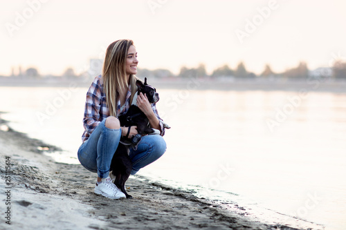 Woman with boston terrier black and white dog at the sandy beach