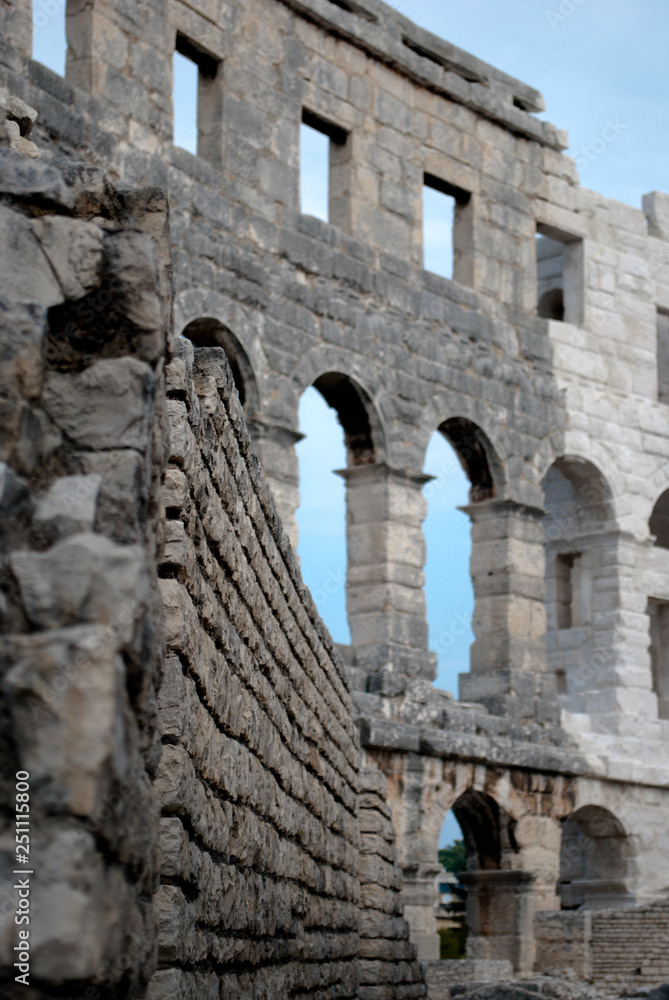Ancient Roman Amphitheater in Pula, Croatia. Popular Touristic Destination of Istria at Adriatic Sea. Defocused Flowers on the Foreground. Copy Space.