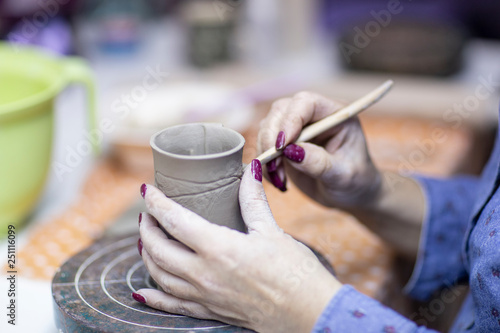 Hands of artist who make a mug from ceramic clay in studio