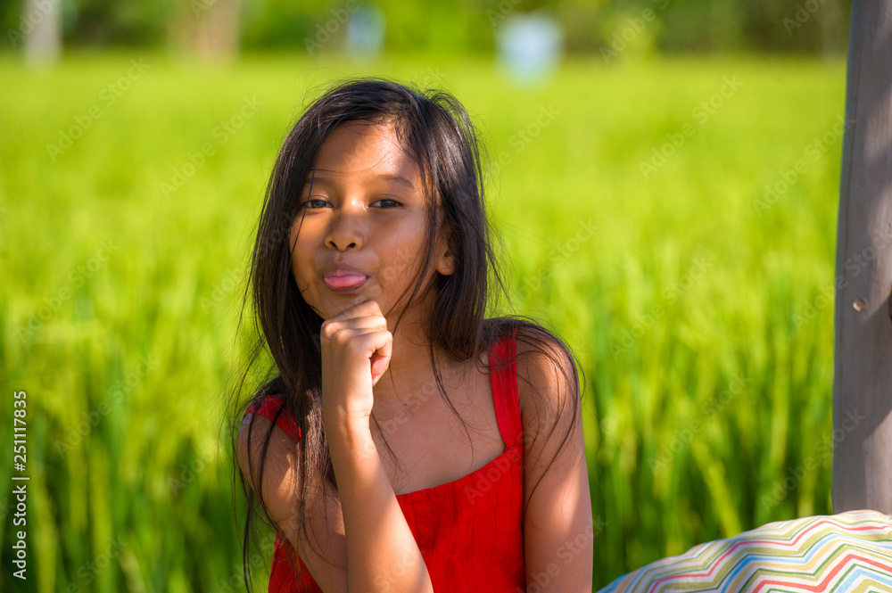 outdoors lifestyle portrait of beautiful and sweet young girl happy posing doing playful faces, the child dressed in a red dress isolated on green field landscape outdoors lifestyle portrait of beautiful and sweet young girl happy posing doing playful faces, the child dressed in a red dress isolated on green field landscape