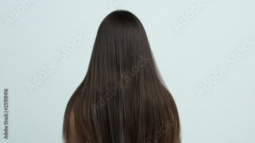 Woman moves long hair. Rear view. Girl shakes long straight hair. Female model is fluttering hair.   Slow motion footage. Rear view.