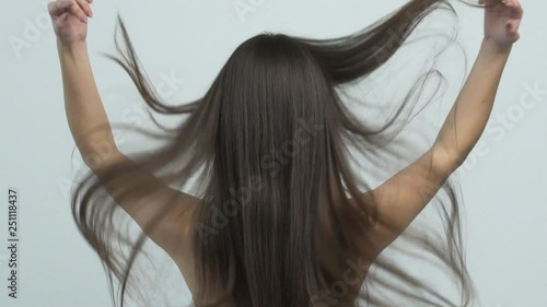 Woman moves long hair. Rear view. Girl shakes long straight hair. Female model is fluttering hair.   Slow motion footage. Rear view.