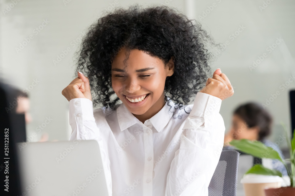 Black female looking at laptop screen working in office Black female looking at laptop screen working in office