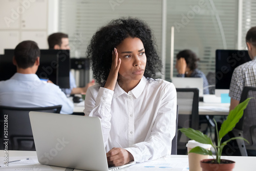 Black female sitting at work suffering from headache