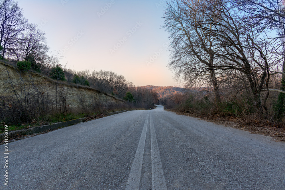 a rural road with a background of sunset and the blue sky