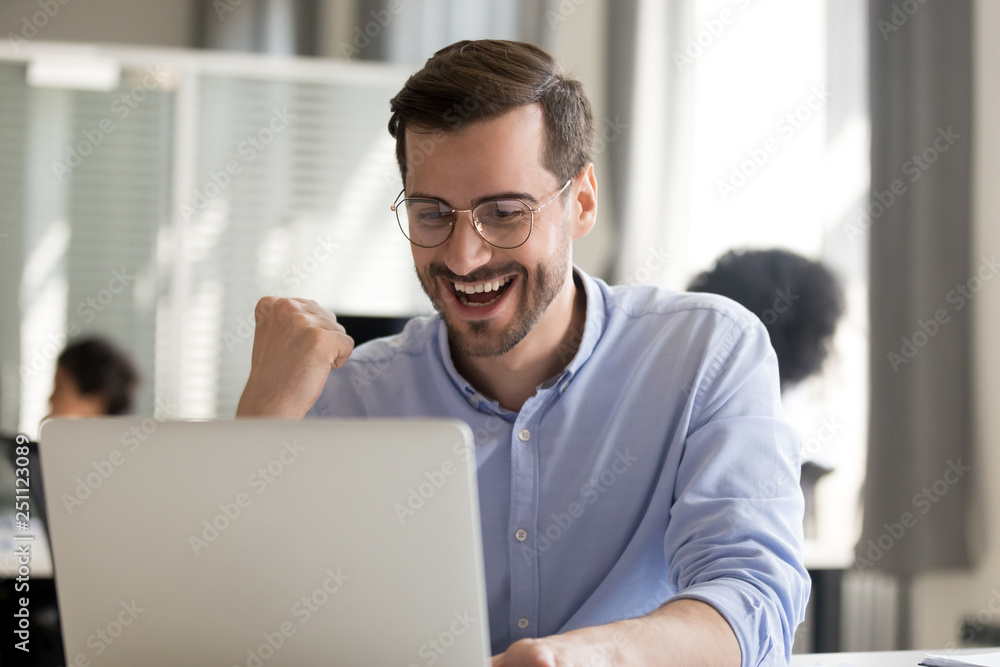 Excited male worker reading great offer sitting in office Excited male worker reading great offer sitting in office