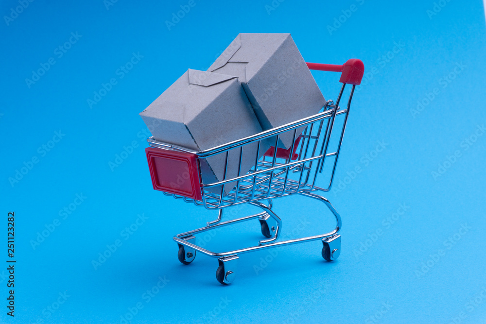 Shopping cart and box on blue background, business and shopping concept. Selective focus Shopping cart and box on blue background, business and shopping concept. Selective focus