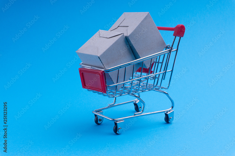 Shopping cart and box on blue background, business and shopping concept. Selective focus Shopping cart and box on blue background, business and shopping concept. Selective focus