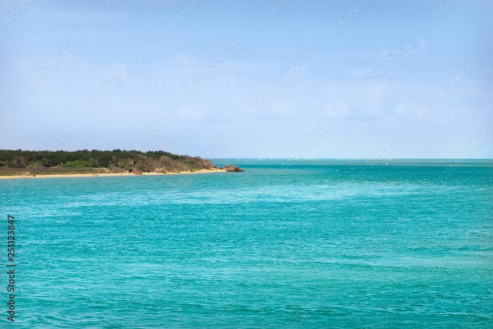 Ocean coast with turquoise water and  white clouds sunny blue sky. Beautiful seascape. Idyllic vacation concept.