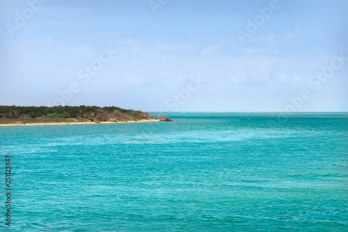 Ocean coast with turquoise water and white clouds sunny blue sky. Beautiful seascape. Idyllic vacation concept.