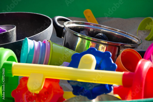 Some toy s in the sandbox in all colors and some pans with a green background