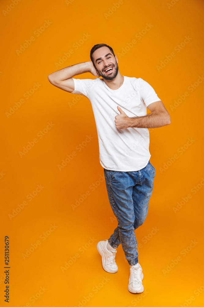 Full length image of cheerful man 30s with beard and mustache showing thumb up while standing, isolated over yellow background Full length image of cheerful man 30s with beard and mustache showing thumb up while standing, isolated over yellow background