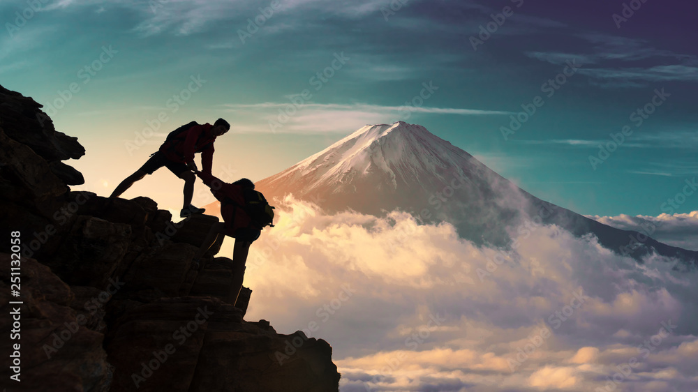 Young asian couple hikers climbing up on the peak of mountain near mountain fuji .Climbing ,Helps and Team work concept  - obrazy, fototapety, plakaty 