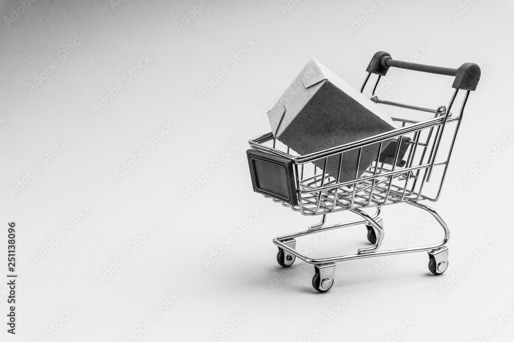 Shopping cart and box on black and white background, business and shopping concept. Selective focus Shopping cart and box on black and white background, business and shopping concept. Selective focus