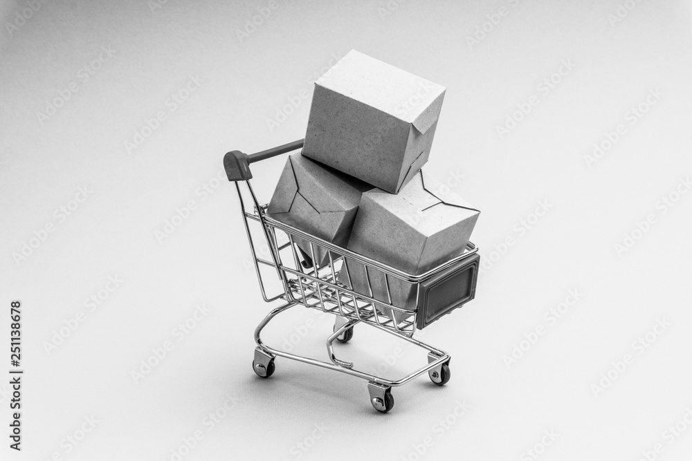 Shopping cart and box on black and white background, business and shopping concept. Selective focus Shopping cart and box on black and white background, business and shopping concept. Selective focus