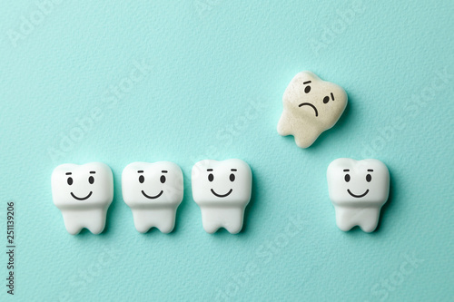Healthy white teeth are smiling and removing yellow tooth with caries is sad against green mint backgroundhook.