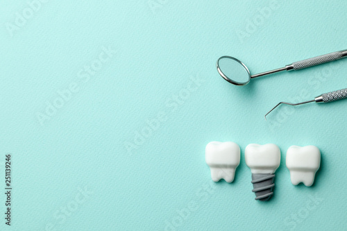 Healthy white teeth and implants on green mint background and dentist tools mirror, hook. Copy space for text.