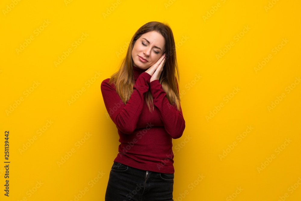 Woman with turtleneck over yellow wall making sleep gesture in dorable expression Woman with turtleneck over yellow wall making sleep gesture in dorable expression