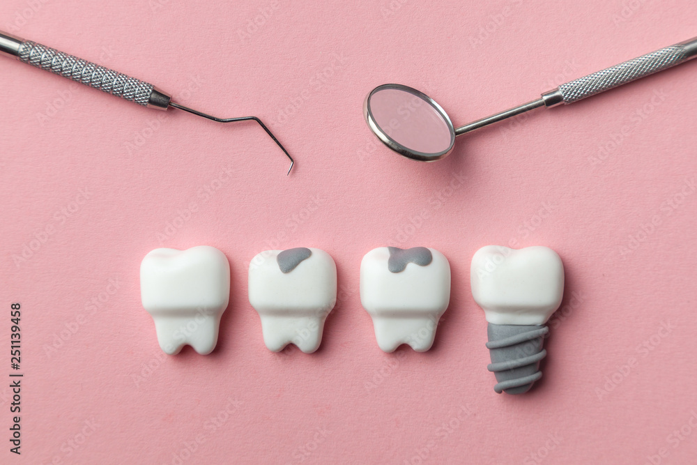 Healthy white teeth and implant and the tooth with caries sad on pink background. Dentist tools mirror, hook. Healthy white teeth and implant and the tooth with caries sad on pink background. Dentist tools mirror, hook.