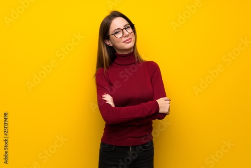 Wall Mural Woman with turtleneck over yellow wall with glasses and happy