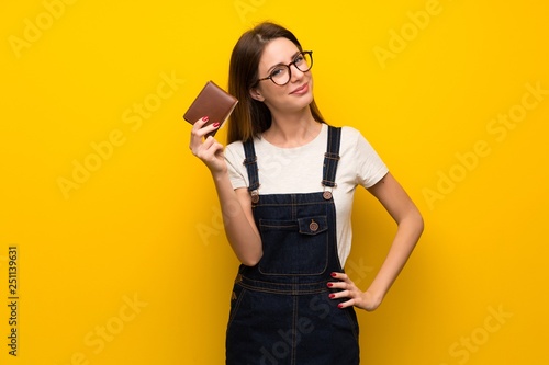 Woman over yellow wall holding a wallet