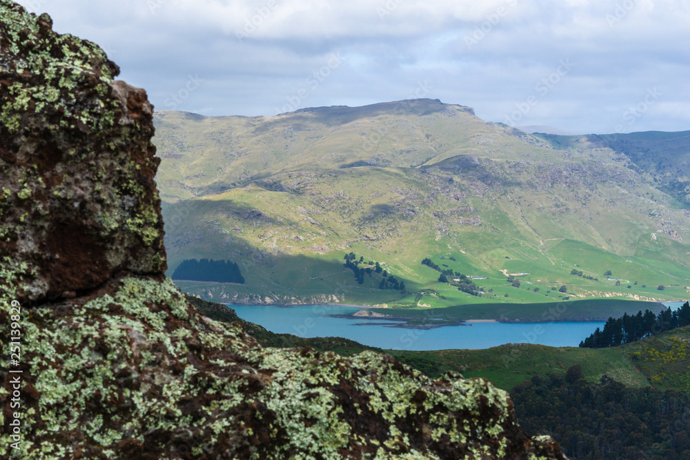 Rocks in foreground and bay surrounded by green mountains in the background