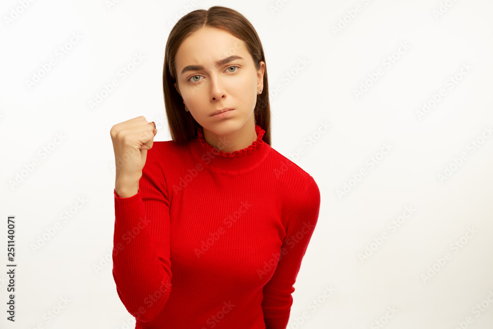 Irritated angry woman frowns face, has dissatisfied facial expression, wears casual red clothes, has long straight hair, threats about something, isolated over white background Irritated angry woman frowns face, has dissatisfied facial expression, wears casual red clothes, has long straight hair, threats about something, isolated over white background