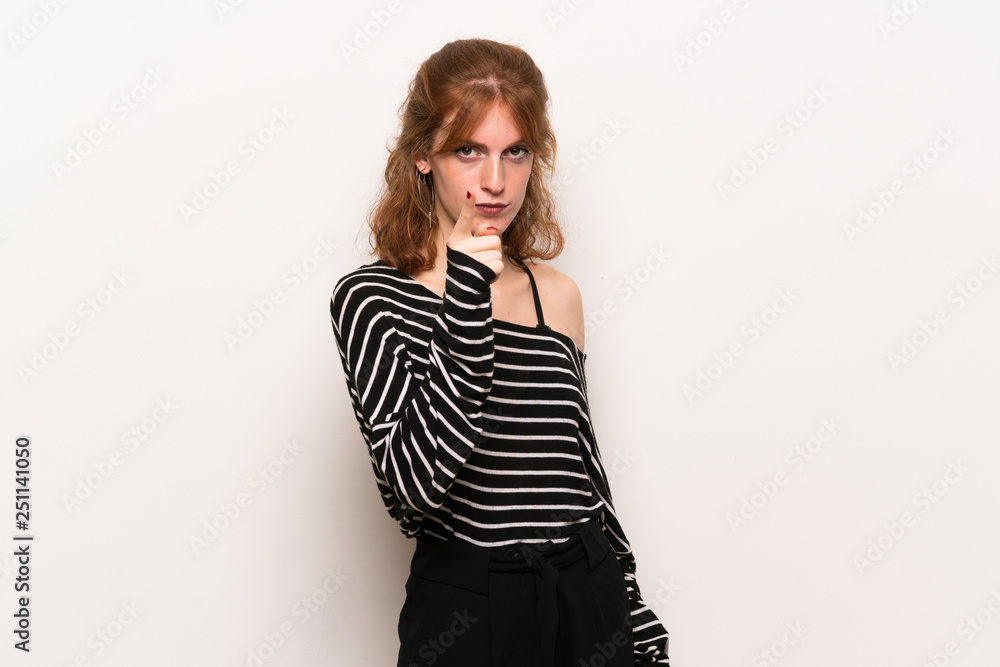 Young redhead woman over white wall frustrated by a bad situation and pointing to the front Young redhead woman over white wall frustrated by a bad situation and pointing to the front