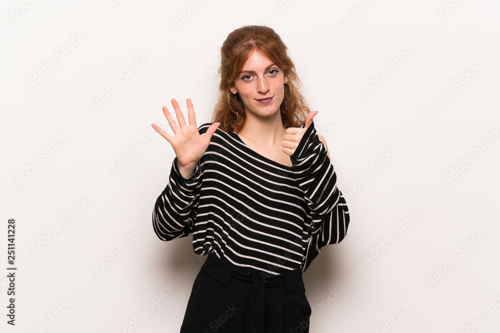 Young redhead woman over white wall counting six with fingers Young redhead woman over white wall counting six with fingers