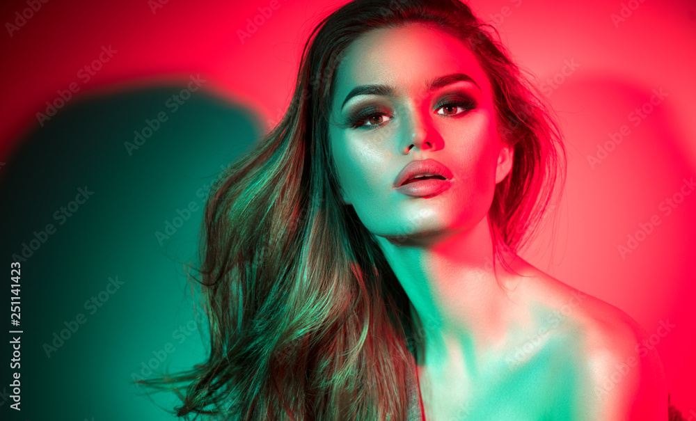 Fashion model brunette woman in colorful bright neon lights posing in studio. Beautiful sexy girl, trendy. Art design colorful makeup