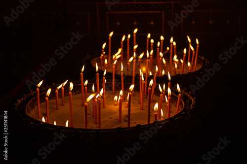 Candles lit in a stand with sand in a church in Prague