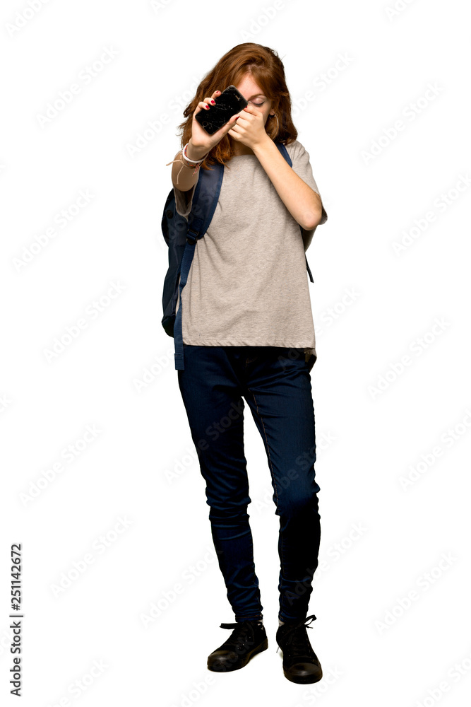 A full-length shot of a Young redhead student upset with a broken phone over isolated white background A full-length shot of a Young redhead student upset with a broken phone over isolated white background