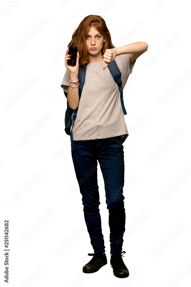 A full-length shot of a Young redhead student with a broken phone over isolated white background A full-length shot of a Young redhead student with a broken phone over isolated white background