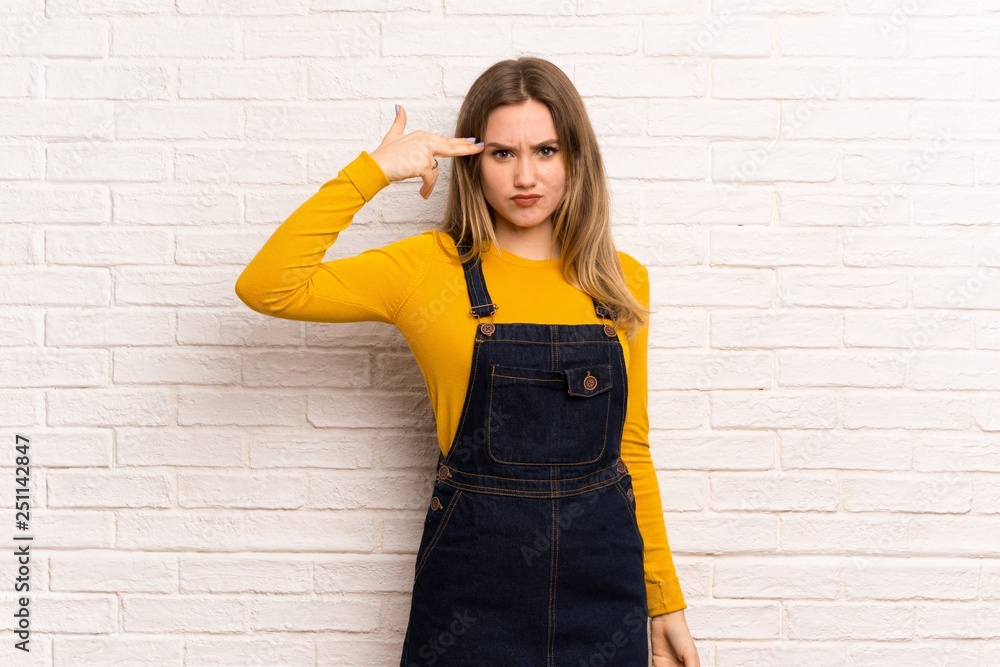 Teenager girl over white brick wall with problems making suicide gesture Teenager girl over white brick wall with problems making suicide gesture