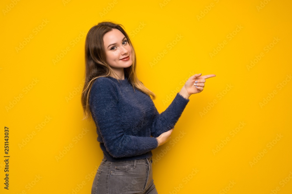 Teenager girl over yellow wall pointing finger to the side Teenager girl over yellow wall pointing finger to the side