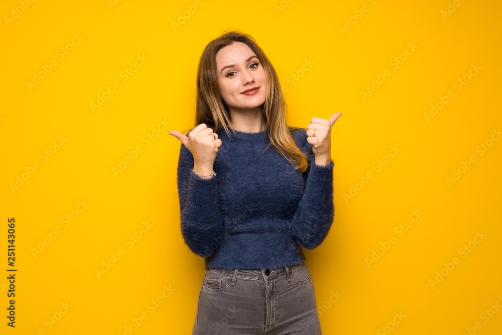 Teenager girl over yellow wall giving a thumbs up gesture and smiling Teenager girl over yellow wall giving a thumbs up gesture and smiling