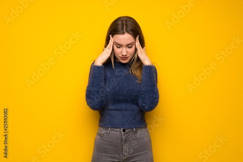 Teenager girl over yellow wall with headache
