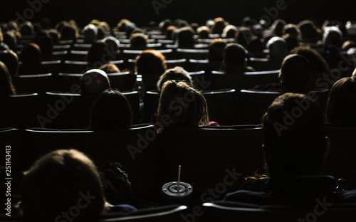 People in the cinema watching a movie, illuminated by the big screen