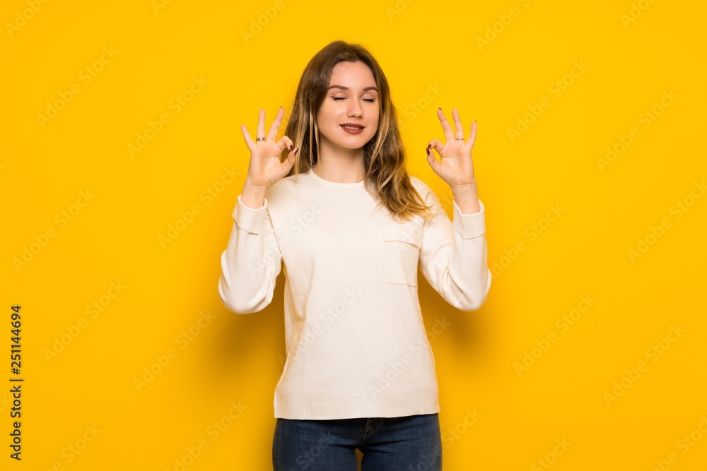 Teenager girl over yellow wall in zen pose Teenager girl over yellow wall in zen pose
