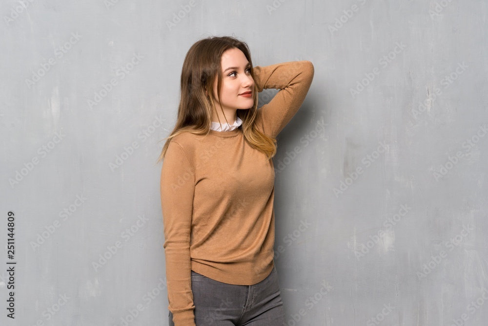 Fototapeta premium Teenager girl over textured wall thinking an idea while scratching head