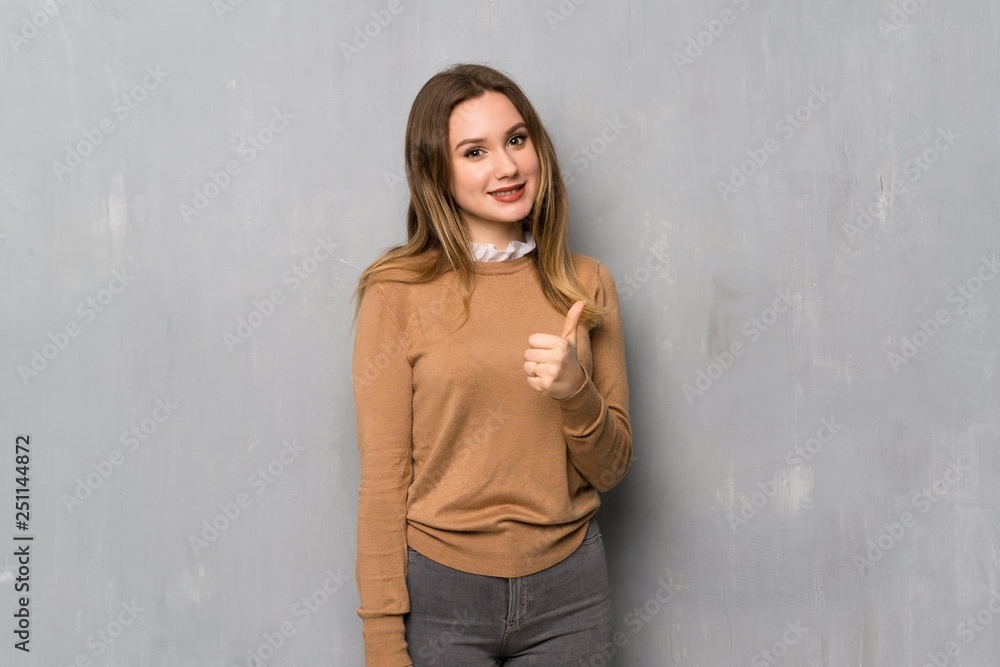 Teenager girl over textured wall giving a thumbs up gesture and smiling Teenager girl over textured wall giving a thumbs up gesture and smiling