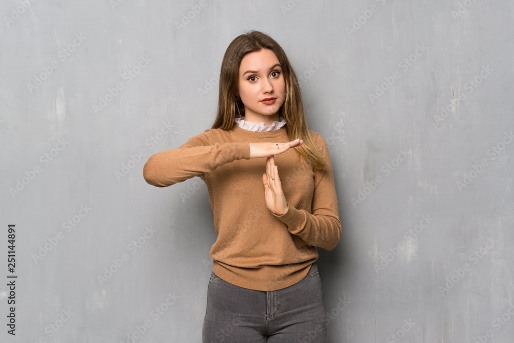 Teenager girl over textured wall making time out gesture