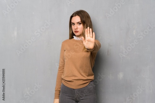 Teenager girl over textured wall making stop gesture denying a situation that thinks wrong